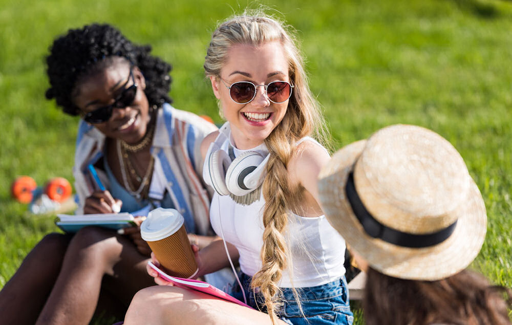 group of friends sitting on grass while smiling