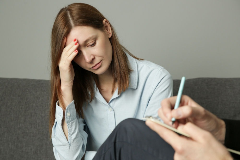 a woman with hand on head in distress in therapy