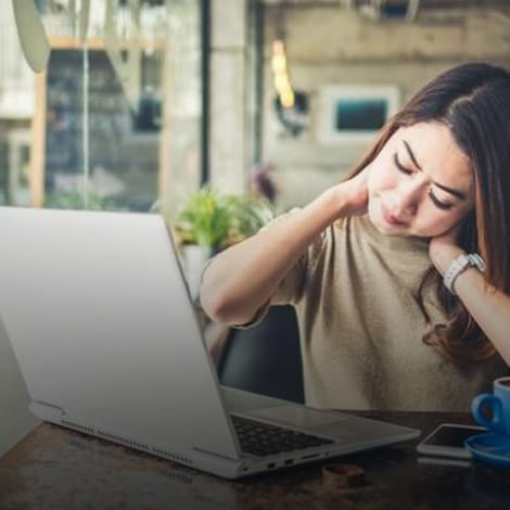 woman holding neck at cyber cafe needing chronic pain management programs