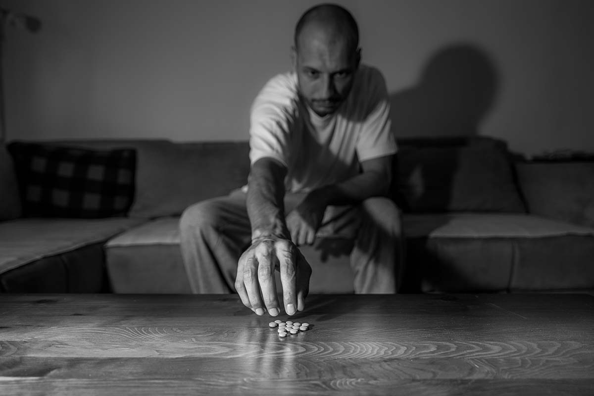man reaching for pills because of his psychological dependence