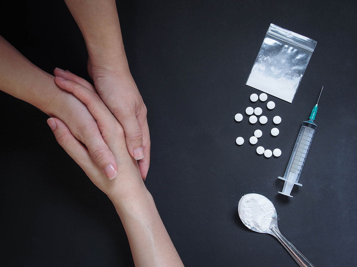 hands reaching out to help someone overdosing showing how to stop drug abuse