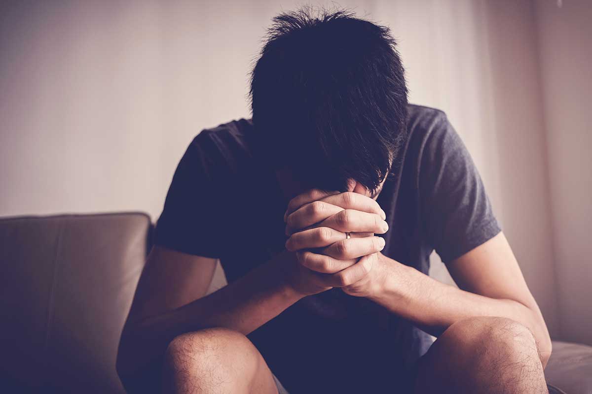 a man with head in hands wondering about bipolar vs PTSD