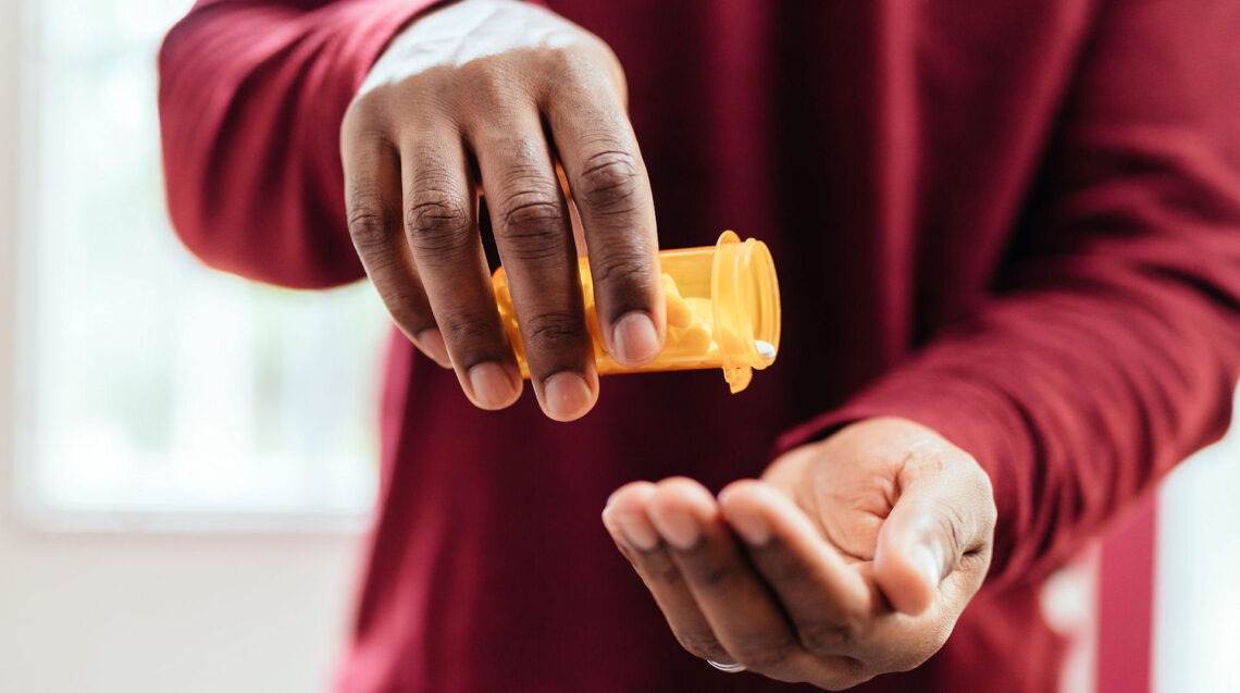 a man pouring pills into hand