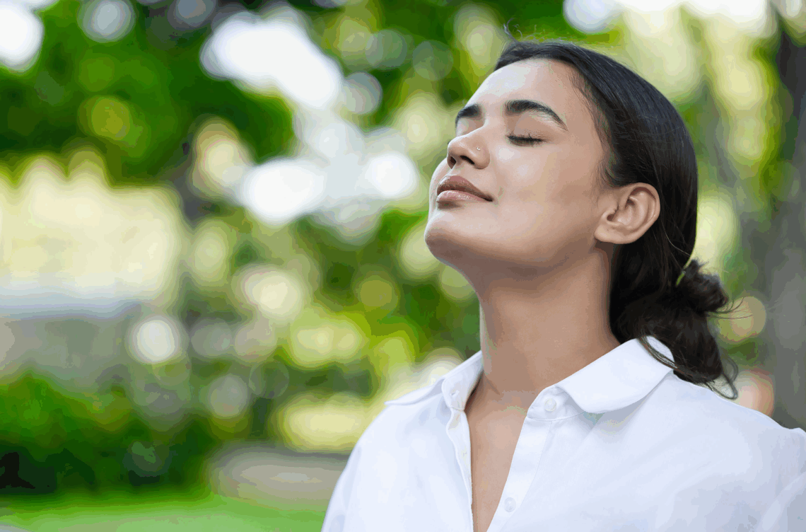 A woman with eyes closed in nature, showing the positivity of being sober